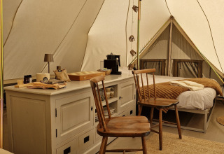Interieur van een Bell tent bij Thuysgrond in Nederland, met houten stoelen, bedden en warme sfeer.