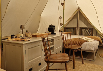 Gemütliches Bell-Zelt-Interieur bei Thuysgrond, Niederlande, mit Holzstühlen, Kommode und Betten.