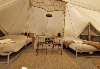 Innenaufnahme des Bell Tent Tipis bei Thuysgrond in den Niederlanden mit zwei Betten und Holzmöbeln.