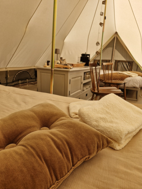 Interieur van een Bell tent op Thuysgrond in Nederland, met zachte kussens, stoelen en een deken.