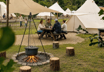 Groep aan picknicktafel bij Basecamp Bell tent op Thuysgrond, Nederland, tussen verschillende tipitenten.
