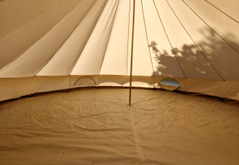 Binnenzicht van een Basecamp Bell tent op Thuysgrond, Nederland, met zonlicht en boomschaduwen.
