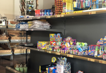 Shelf filled with various candies and souvenirs in a shop at a glamping accommodation, well-lit area.