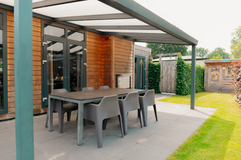 Overdekt terras met tafel en stoelen bij Veluwe Villa aan De Boshoek-lodge in Nederland.