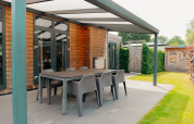 Overdekt terras met eettafel en stoelen bij Veluwe Villa op De Boshoek-lodge in Nederland.