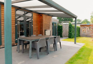 Überdachte Terrasse mit Esstisch und Stühlen an der Veluwe Villa-Lodge bei De Boshoek, Niederlande.