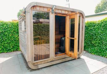 Outdoor wooden sauna with glass windows and open door at Veluwe Villa, De Boshoek, Netherlands.