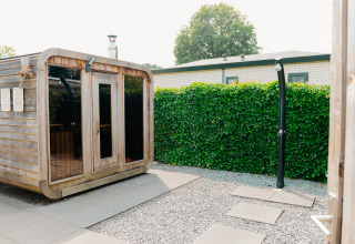 Außenansicht einer Sauna und Außendusche bei Veluwe Villa im De Boshoek, umgeben von Grün.