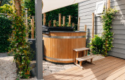 Houten buitenspa met opstapje en groene beplanting bij Veluwelodge XL, De Boshoek, Nederland.