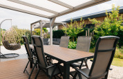 Buiten terras bij Veluwelodge XL op De Boshoek in Nederland met eettafel, loungestoelen en hangstoel.