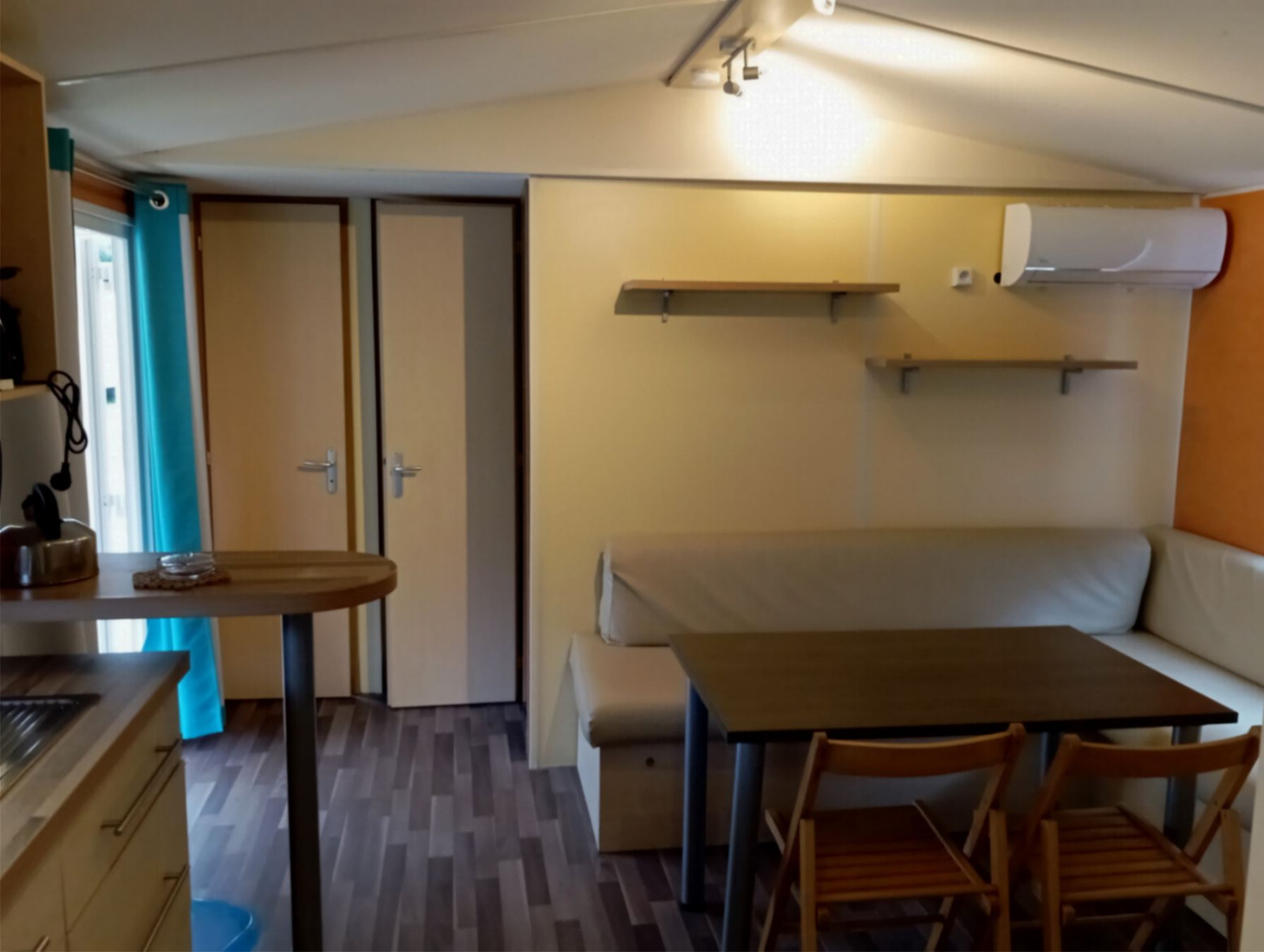 Interieur van Mobile Home Comfort bij Camping Seasonova Sous le Moulin in Frankrijk met bank en eethoek.