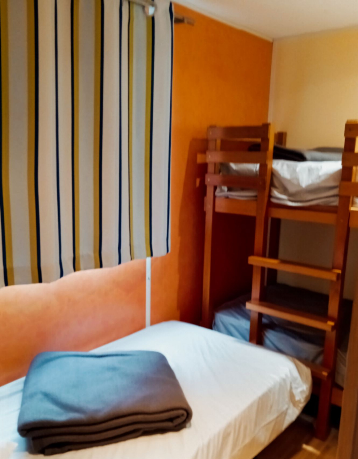 Gezellige kamer met een eenpersoonsbed en stapelbedden in Mobile Home Comfort, Camping Seasonova Sous le Moulin, Frankrijk.