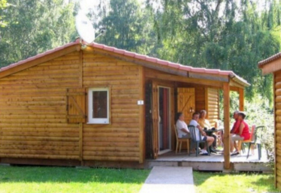 Gruppo di persone sedute sulla veranda del Chalet Eco lodge, immerso nel verde e vicino a baite di legno.