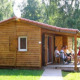 Gruppo di persone sedute sulla veranda del Chalet Eco lodge, immerso nel verde e vicino a baite di legno.