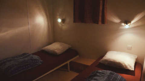 Due letti singoli con cuscini e coperte in una stanza accogliente dello Chalet Eco, Camping Paradis Les Chanterelles, Francia.