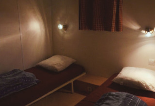 Due letti singoli con cuscini e coperte in una stanza accogliente dello Chalet Eco, Camping Paradis Les Chanterelles, Francia.