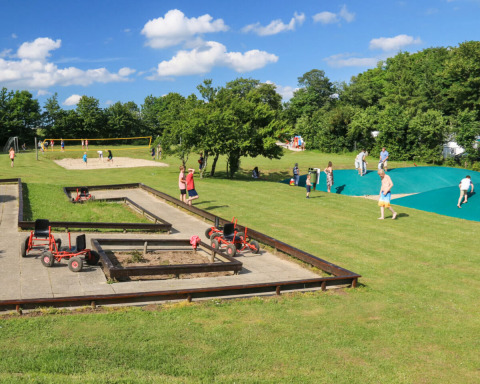 Kinderen en volwassenen genieten van outdooractiviteiten bij Terrassen Camping in Denemarken op een zonnige dag.
