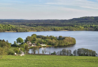 Landschap nabij Silkeborg, Denemarken, met meer, groene velden en omliggend bos in het zonlicht.