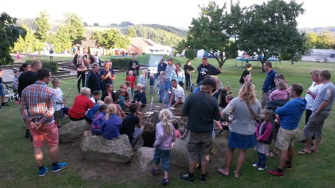 En stor gruppe mennesker samles omkring et bål på Terrassen Camping i region Midtjylland, Danmark.