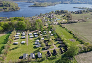 Luftfoto af Terrassen Camping i Region Midtjylland, Danmark, med hytter, campingvogne og søudsigt.