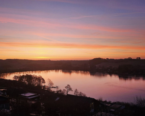 Solnedgang over søen ved Terrassen Camping i Midtjylland, Danmark, med smukke farver i himlen.
