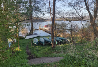 Udsigt til små både og en mole ved søen omgivet af træer på Terrassen Camping i Danmark om foråret.