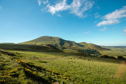 Bjergrigt landskab nær Saint-Rémy-sur-Durolle i Auvergne-Rhône-Alpes, Frankrig, under en blå himmel.
