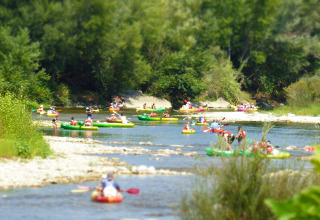 Menschen paddeln in bunten Kanus auf einem Fluss, umgeben von grünem Wald bei Saint-Rémy-sur-Durolle, Frankreich.