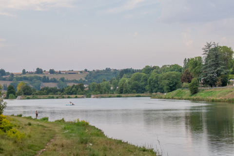 Ruhiger See bei Roybon, Auvergne-Rhône-Alpes, Frankreich, umgeben von Wald, Wiesen und einem Angler.