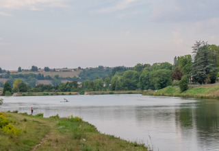 Ruhiger See bei Roybon, Auvergne-Rhône-Alpes, Frankreich, umgeben von Wald, Wiesen und einem Angler.