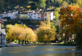Bord de rivière à Roybon, Auvergne-Rhône-Alpes, France, avec arbres d’automne et maisons perchées ensoleillées.