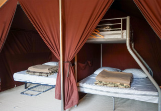 Interno della tenda safari Ponza a Onlycamp Camping Le Lac de Roybon in Francia, con letti e coperte.