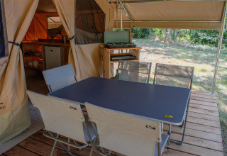 Zona pranzo esterna nella tenda safari Ponza presso Onlycamp Camping Le Lac de Roybon in Francia, con tavolo e sedie.