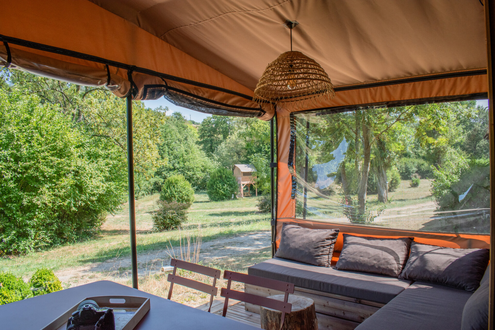 Sfeervol interieur van een safaritent met tweepersoonsbed, houten planken, ramen en gordijnen.