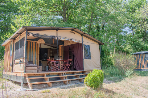 Tiny House Galli, una casa nella natura con veranda e mobili esterni, immersa in un verde bosco.