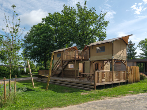Treehouse tent with bubble tub at Holiday park Mölke in the Netherlands, surrounded by greenery.