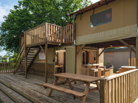Treehouse tent with deck, picnic seating and stairs at Holiday park Mölke, Netherlands, outdoor view.