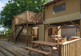 Treehouse tent with deck, picnic seating and stairs at Holiday park Mölke, Netherlands, outdoor view.