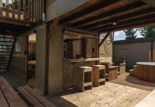 Boomhut tent met bubbelbad bij Vakantiepark Mölke in Nederland, met rustieke houten meubels en buitenruimte.