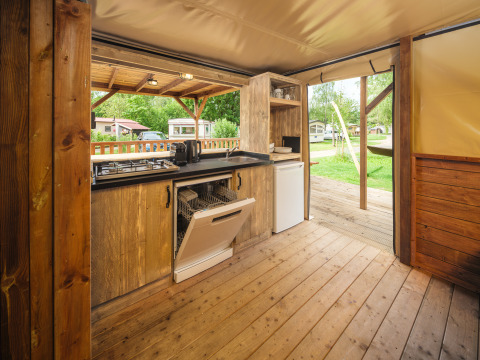 Outdoor kitchen with wood flooring, open dishwasher, and view of campsite at Holiday Park Mölke, Netherlands.