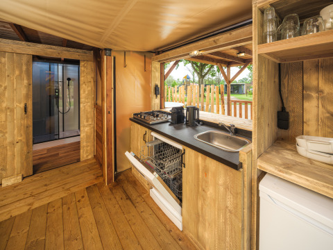 Interieur van een boomhuttent met keuken en houten inrichting bij Holiday park Mölke in Nederland.