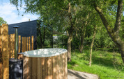 Bain nordique extérieur en bois au River Mirrorlodge, Holiday park Mölke, Pays-Bas, entouré d’arbres.