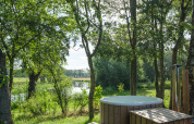 Bain nordique en bois au River Mirrorlodge, Holiday park Mölke, entouré d’arbres et d’une rivière aux Pays-Bas.