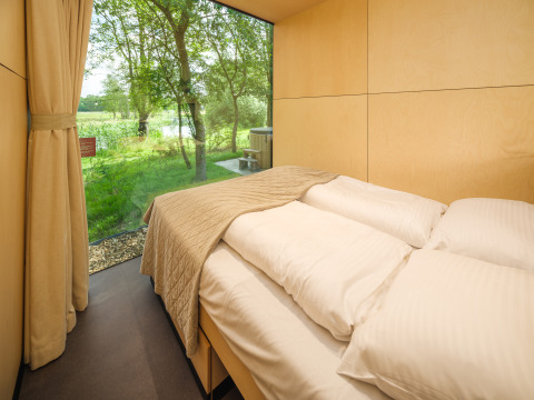 Slaapkamer in de River Mirrorlodge bij vakantiepark Mölke in Nederland met panoramisch uitzicht op natuurgebied.