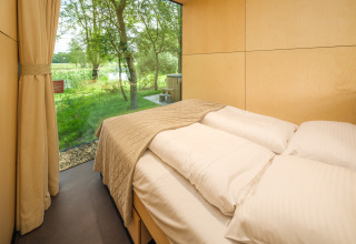 Slaapkamer in de River Mirrorlodge bij vakantiepark Mölke in Nederland met panoramisch uitzicht op natuurgebied.