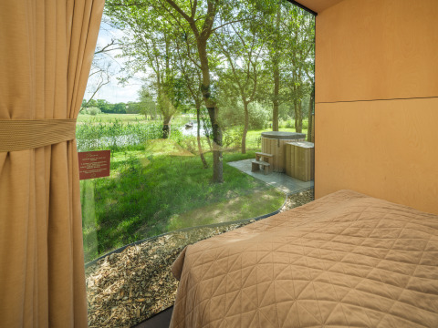 Uitzicht vanuit het bed in River Mirrorlodge bij Holiday park Mölke in Nederland, met bomen en rivier.