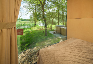 Uitzicht vanuit het bed in River Mirrorlodge bij Holiday park Mölke in Nederland, met bomen en rivier.