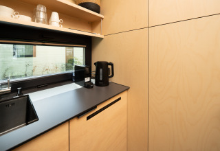 Moderne kitchenette in River Mirrorlodge bij Holiday park Mölke, Nederland, met waterkoker en kopjes.