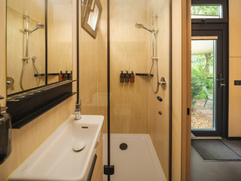 Moderne badkamer met douche en wastafel in de River Mirrorlodge bij vakantiepark Mölke in Nederland.