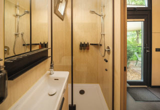 Moderne badkamer met douche en wastafel in de River Mirrorlodge bij vakantiepark Mölke in Nederland.